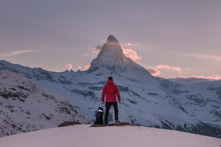 Person mit Hund im Schnee vor dem Matterhorn